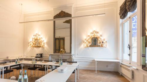 a room with tables and a mirror and chandeliers at Hotel Gravensteen in Ghent