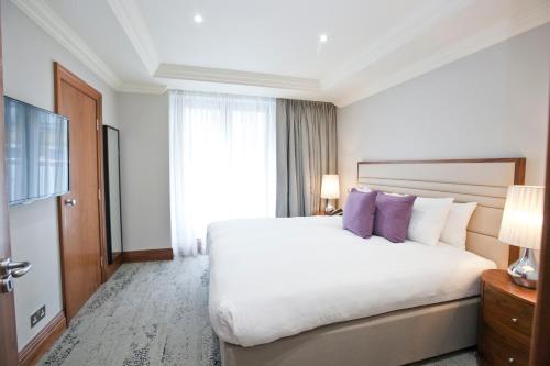 a hotel room with a large bed with purple pillows at Sanctum Maida Vale in London