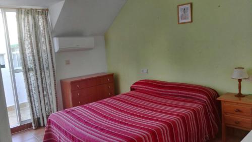 een slaapkamer met een bed met een gestreepte deken bij Apartamento Década Cervantes 19 in Fuengirola