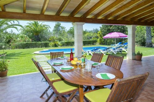 una mesa de madera y sillas en un patio con piscina en Owl Booking Villa Bobis - Family Holidays with Private Pool, en Port de Pollença (Puerto Pollensa)