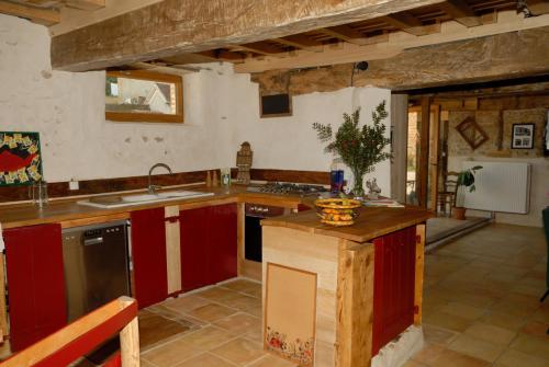 uma grande cozinha com armários vermelhos e um lavatório em Gîte CoMic em Vidouze