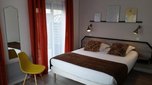 a bedroom with a bed and a yellow chair at Amadour Hôtel in Rocamadour