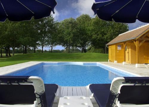 a swimming pool with two chairs and an umbrella at L'Orée des Chênes, The Originals Relais in La Ferté-Saint-Aubin
