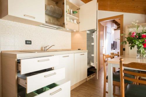 a kitchen with white cabinets and a wooden table at Residence Hotel Miralago in Pergine Valsugana