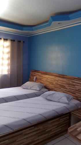 two beds in a bedroom with a blue wall at Hotel Carpe Diem in Sao Paulo