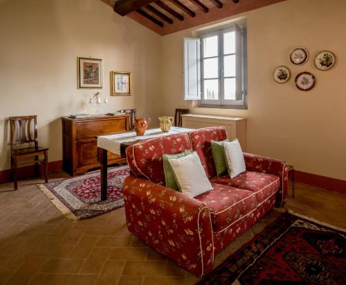 a living room with a red couch and a table at Agriturismo Podere La Rocca in Abbadia di Montepulciano