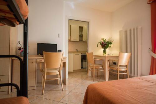 a room with a table and chairs and a kitchen at Residence Hotel Miralago in Pergine Valsugana