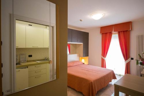 a bedroom with a bed and a kitchen with a mirror at Residence Hotel Miralago in Pergine Valsugana