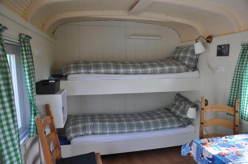 two bunk beds in a small room with a table at Your nice waggon at the Cow's Paradise in Amsterdam