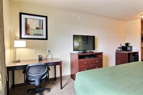 a hotel room with a desk and a bed and a television at AmeriVu inn and Suites - Crookston in Crookston