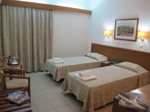 um quarto de hotel com duas camas e uma mesa em Hotel Solomou Athens em Atenas