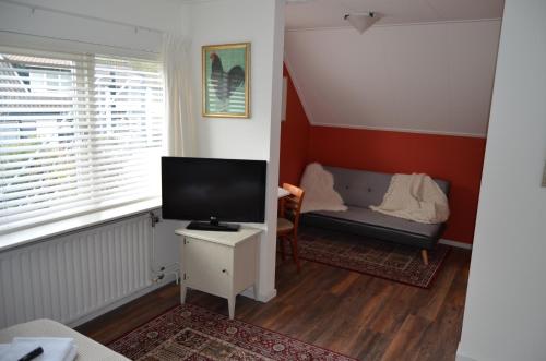 a living room with a television and a couch at Hotel De Waag in Bergen