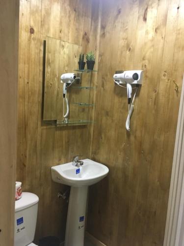 a bathroom with a sink and a toilet and a mirror at Hostal Plaza Chiloe in Castro