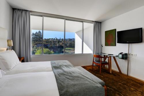 ヴァウにあるBom Sucesso Resortのベッドと大きな窓が備わるホテルルームです。