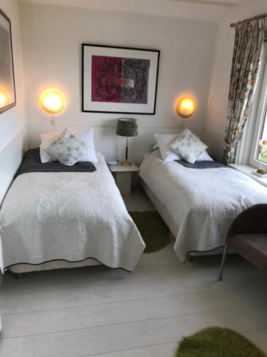 a bedroom with two beds and a window and two lamps at Villa 't Haasduin in Wijk aan Zee