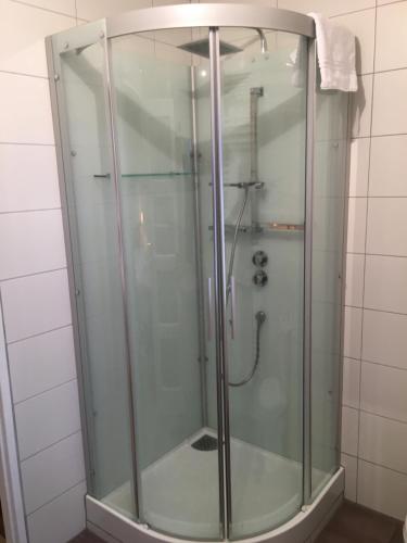 a shower with a glass door in a bathroom at Le Melchior in Sainte-Terre