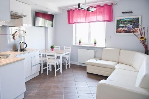uma cozinha e sala de estar com um sofá e uma mesa em Apartamenty Nad Jeziorkiem em Varsóvia