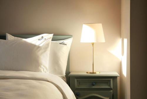 a bed with white pillows and a lamp on a night stand at Conacul Törzburg in Bran