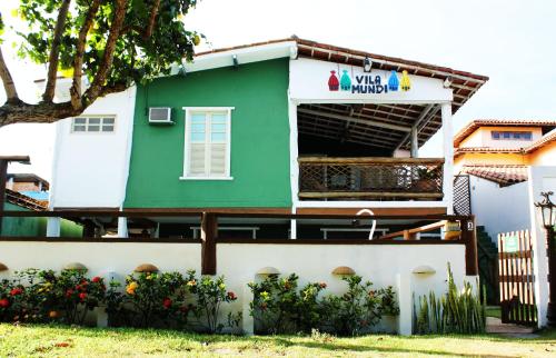 a green and white house with flowers in front of it at Pousada Vila Mundi Itaúnas in Itaúnas