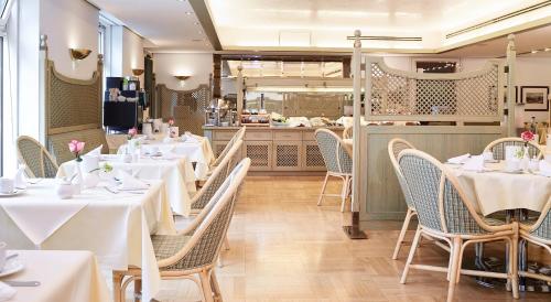 um restaurante com mesas e cadeiras brancas e um balcão em Living Hotel Prinzessin Elisabeth em Munique