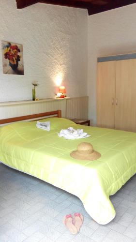 - une chambre dotée d'un grand lit avec un chapeau et des chaussons dans l'établissement Rico Plage, à Figareto