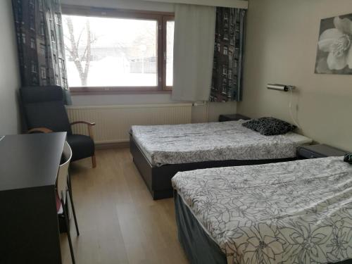 a hotel room with two beds and a window at Hotelli Puustelli Lieksa in Lieksa