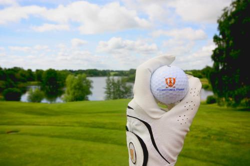 a hand holding up a golf ball on a golf course at Strandgrün Golf- & Spa Resort in Timmendorfer Strand
