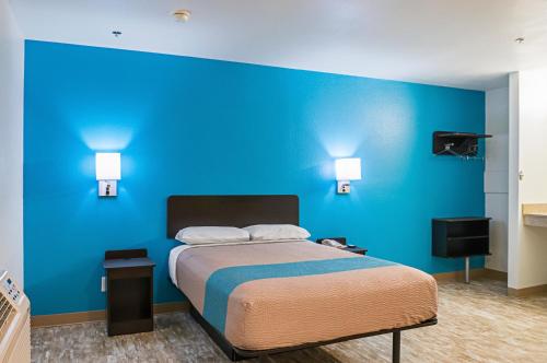 a bedroom with a blue wall and a bed at Motel 6-Bay Saint Louis, MS in Bay Saint Louis