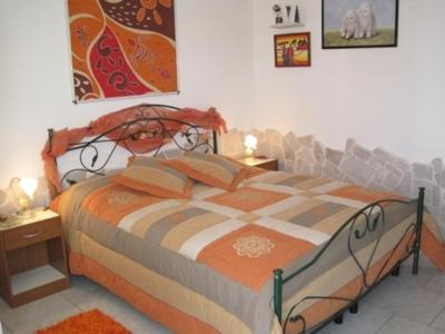 a bedroom with a bed with an orange and white comforter at L'Isola Felice e Trulli Sotto Le Stelle in Castellana Grotte