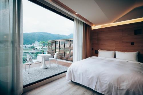 a bedroom with a bed and a large window at Onsense Villa in Jiaoxi