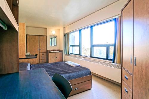 ein Schlafzimmer mit einem Bett und einem großen Fenster in der Unterkunft ZUM MTL Auberge d'été - Université de Montréal in Montreal