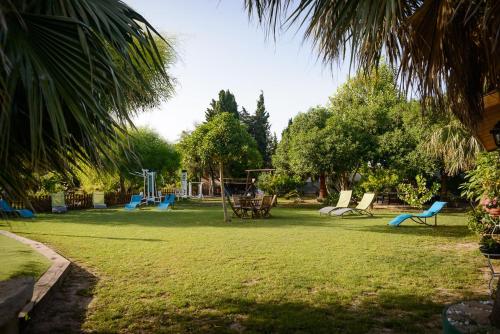 a park with a playground with blue chairs and trees at Lo Racó de Peret in Camarles