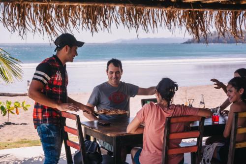 a group of people sitting at a table at the beach at Beach Break Hotel & Surf Camp de Playa Venao in Playa Venao