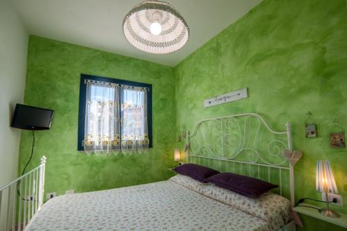 a green bedroom with a bed and a chandelier at Casa Vacanza Sardegna in Valledoria