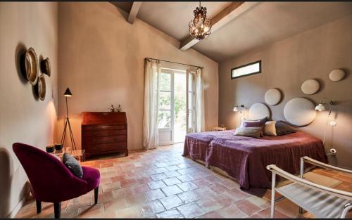 a bedroom with a bed and a chair and a window at Mas De La Baume in Lafare