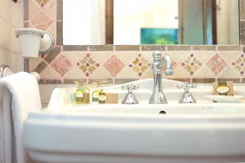 y baño con lavabo blanco y espejo. en L'Agnata di De André Boutique Hotel, en Tempio Pausania