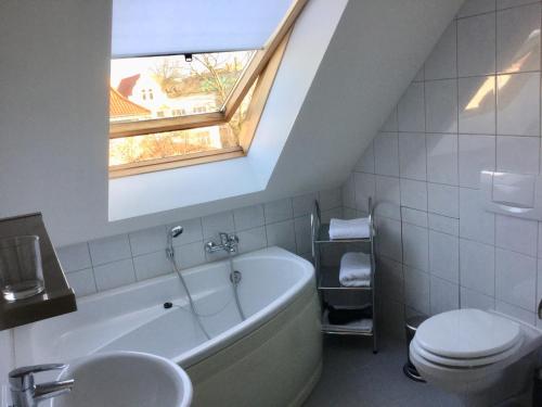 a bathroom with a tub and a toilet and a window at Ferienwohnung Rostock in Rostock