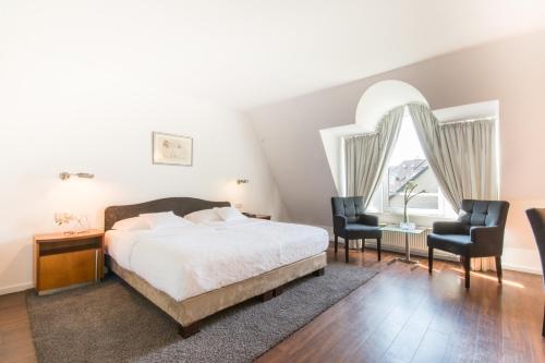 1 Schlafzimmer mit einem Bett, 2 Stühlen und einem Fenster in der Unterkunft Gartenhotel Luisental in Mülheim an der Ruhr