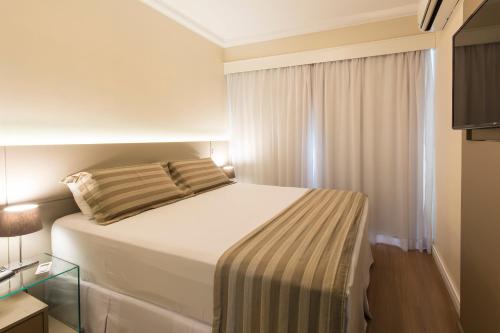 a bedroom with a large bed with a window at Tsue The Palace Flats in Sao Paulo