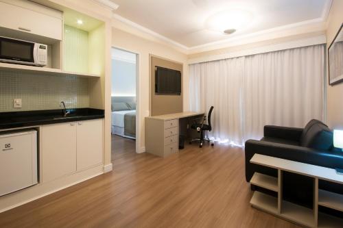 a kitchen and a living room with a couch and a desk at Tsue The Palace Flats in Sao Paulo