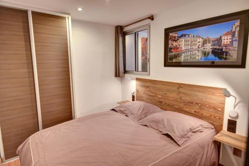 um quarto com uma cama com uma cabeceira de madeira em L'atout charme em Annecy