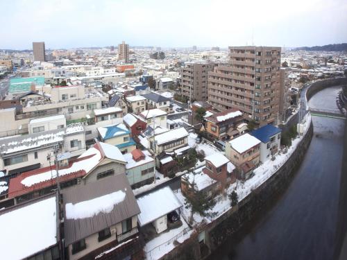 a city with snow covered buildings and a river at APA Hotel Akita Senshu Koen in Akita