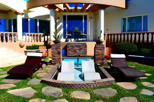 einen Hinterhof mit Pool und Stühlen und ein Haus in der Unterkunft La Mansión Residency Suites Ensenada in Ensenada