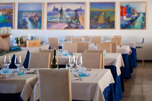 a restaurant with white tables and chairs with wine glasses at Hotel Garden Sea Wellness & Spa 4 stelle superior in Caorle