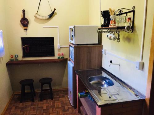 a small kitchen with a sink and a microwave at Casa Santos Dumont in Gramado