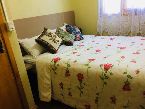 1 cama con edredón de flores y almohadas en Casa Santos Dumont, en Gramado