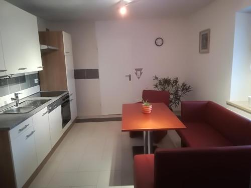 a kitchen with a small table and a red couch at Ferienhaus Kurzbach in Velden