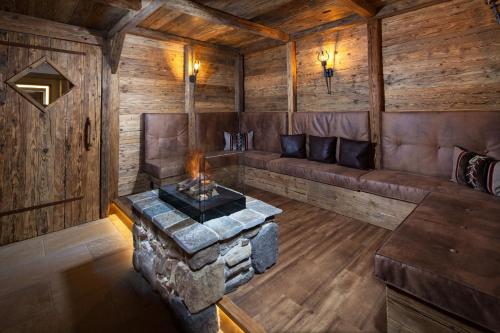 una habitación con sofá y chimenea en una cabaña en Alm- & Wellnesshotel Alpenhof, en Schönau am Königssee