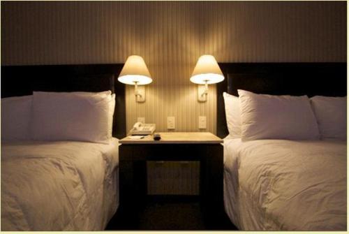 two beds in a hotel room with two lamps at Hotel Gobernador in Durango