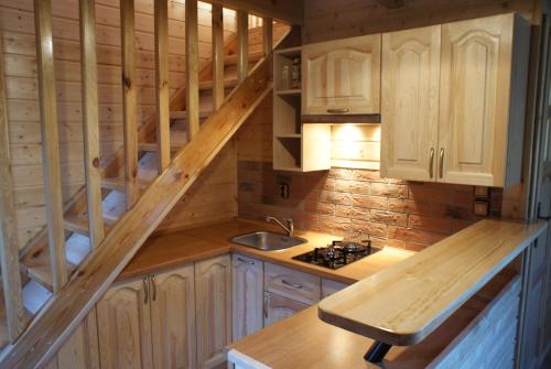 a kitchen with wooden cabinets and a staircase in a cabin at Wczasy u Juliana in Drewnica
